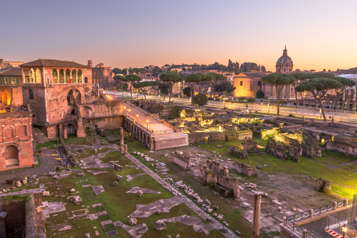 The Roman Forum in Rome, Italy, contains the remains of temples, columns, basilicas and other structures from the ancient city. Evening light illuminates the archaeological site beneath Rome&rsquo;s historic skyline.