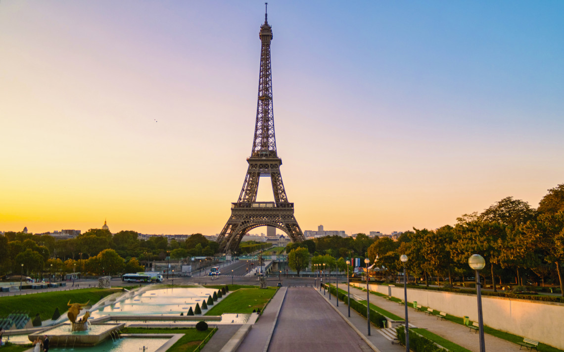 Eiffel Tower viewed from the Trocad&eacute;ro area in Paris at sunset, with landscaped fountains and gardens extending toward the landmark.