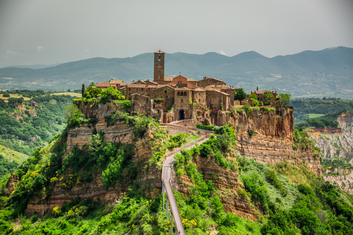 Civita di Bagnoregio stands on a high tuff plateau in Lazio, Italy, surrounded by the eroded Valle dei Calanchi. A long pedestrian bridge provides access to the compact medieval village.