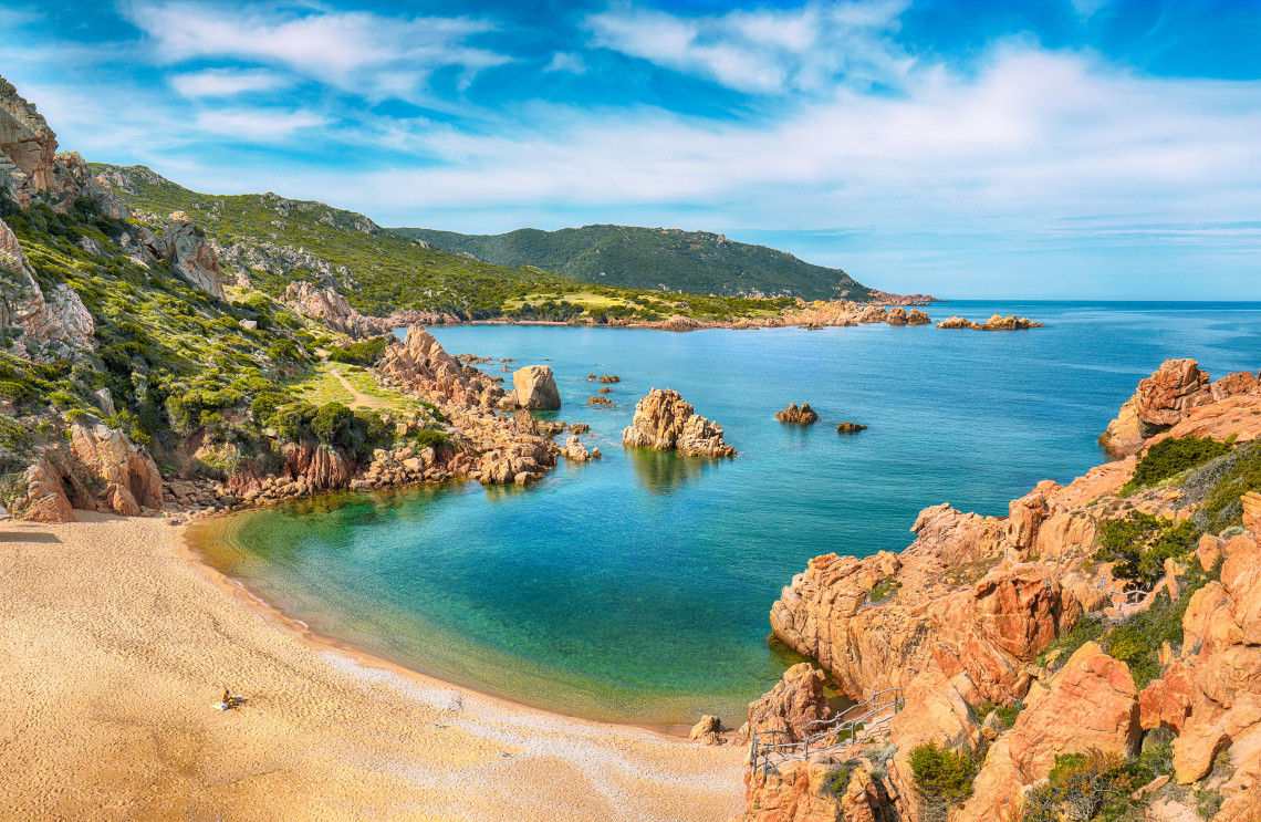 Secluded sandy cove with turquoise water and red granite rocks at Li Cossi Beach, Costa Paradiso, Sardinia, Italy