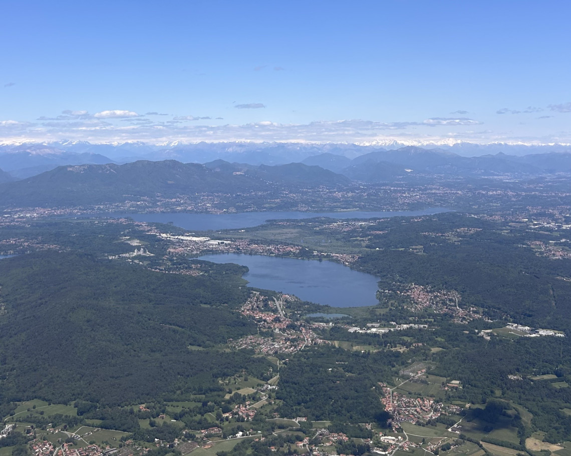 Aerial view of Lake Varese in the foreground and Lake Maggiore in the background surrounded by forested hills with the snow capped Alps on the horizon, Lombardy, Italy
