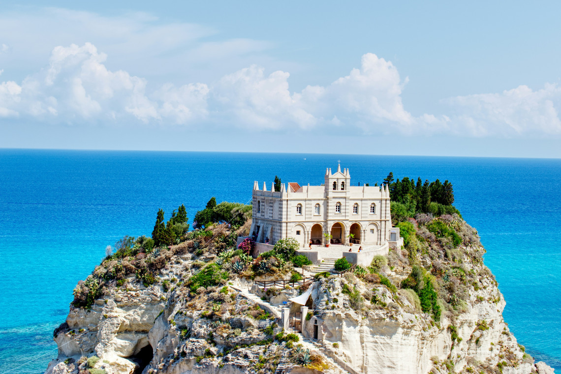 White sanctuary of Santa Maria dell'Isola perched on a rocky cliff above the turquoise Tyrrhenian Sea in Tropea, Calabria, Italy