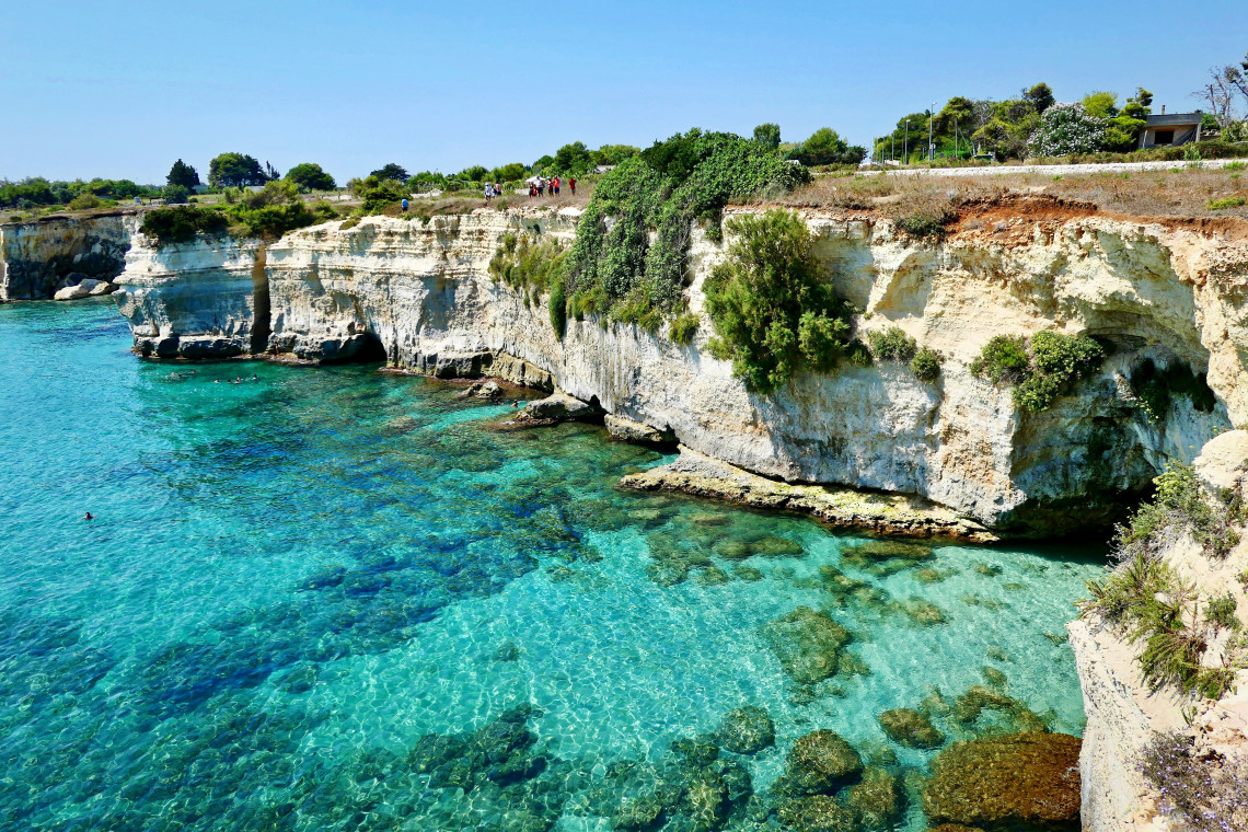 Pale limestone cliffs meeting transparent turquoise water at Torre Sant&rsquo;Andrea in Melendugno, Puglia, along the Adriatic coast of Salento.