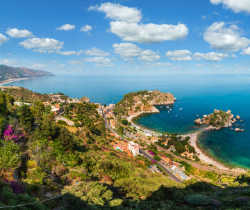 Panoramic aerial view of Taormina coastline with Isola Bella nature reserve nestled in a turquoise bay surrounded by Mediterranean vegetation, Sicily, Italy