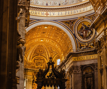 Interior of St. Peter’s Basilica in Vatican City, showing richly decorated arches, gilded ceilings and the monumental bronze baldachin above the papal altar.