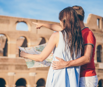 Couple standing with a map in front of the Colosseum in Rome, planning their first Italy itinerary, Rome, Italy