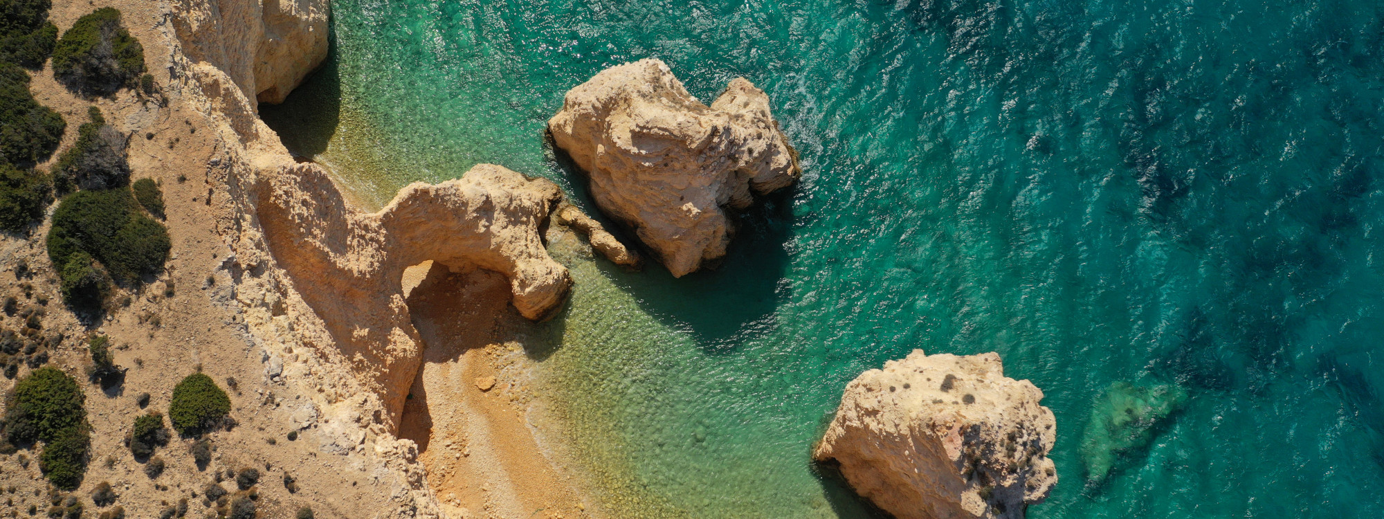 Aerial view of Praia da Marinha in Lagoa, with golden limestone cliffs, secluded sandy coves and distinctive rock formations surrounded by clear turquoise Atlantic water.