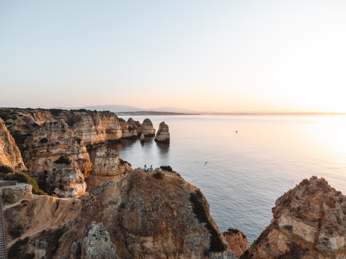 Sunset view over the limestone cliffs and sea stacks of Ponta da Piedade in Lagos, Algarve, Portugal. Calm Atlantic waters surround the rock formations along the southern Portuguese coast.