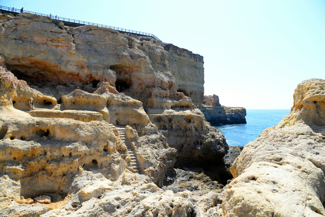 Weathered golden limestone formations, natural cavities and stone steps lead toward the Atlantic Ocean at Algar Seco near Carvoeiro in the Algarve.