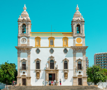 Front façade of the Sé de Faro Cathedral in Faro, Algarve, Portugal, featuring twin bell towers, whitewashed walls, and baroque architectural details. Located in Faro's historic old town, the cathedral is one of the city's most important religious and cul